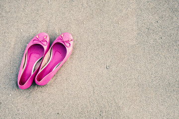 Fototapeta na wymiar Pink feminine shoes on a sandy beach, Film simulation