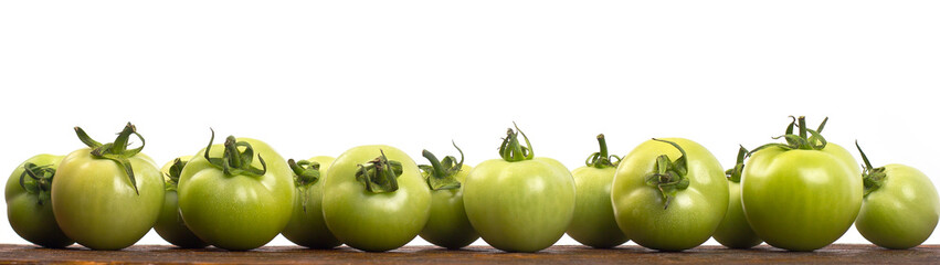 green tomatoes on a wooden shelf with a white background