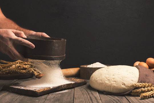 Baker sifts through the flour on a wooden table