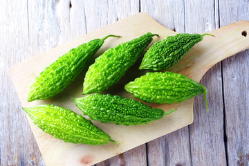 Close up of green fresh bitter gourd on a wooden board.