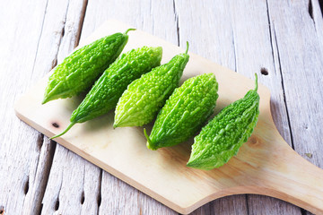 Close up of green fresh bitter gourd on a wooden board.