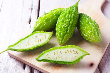 Close up of sliced green fresh bitter gourd on a wooden board.