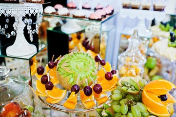 Elegance wedding reception table with food and decor. Carved melon with other fruits