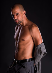 Fototapeta premium Young handsome macho man with open jacket posing on a dark background