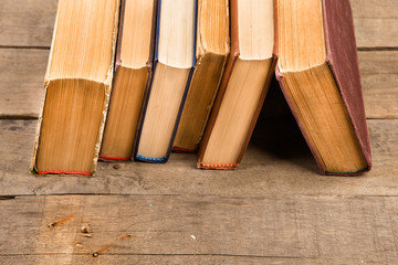 Old and used hardback books or text books on wooden table
