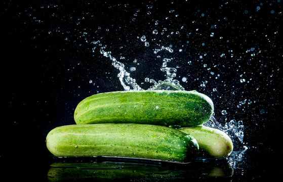 Cucumber with water splash on black background