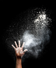 Hand and flour on black background