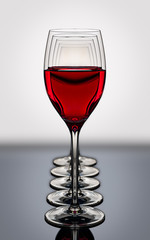 red wine glasses in a row backlighted on a reflective black boar