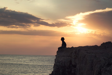 mysterious boy sitting on the precipice of a cliff