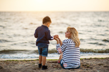 Beautiful woman with a child of four years playing on the beach near the sea