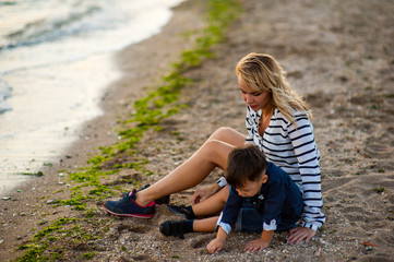 Beautiful woman with a child of four years playing on the beach near the sea