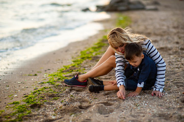 Beautiful woman with a child of four years playing on the beach near the sea