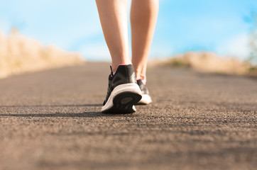 Woman's feet walking on country road. 