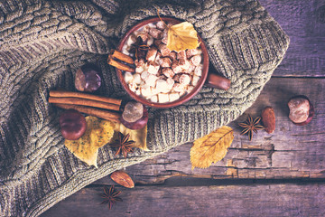Hot cocoa with marshmallows with spices on the old wooden boards. Coffee, cocoa, cinnamon, nuts, star anise, cozy sweater.Autumn Still Life