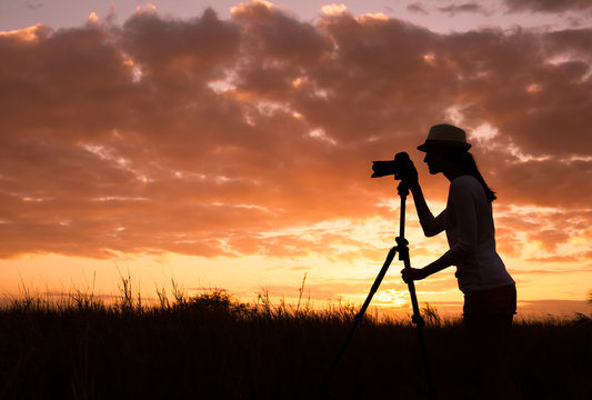 Female photographer capturing a beautiful sunset. 