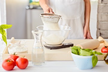 Woman sifting flour through sieve.