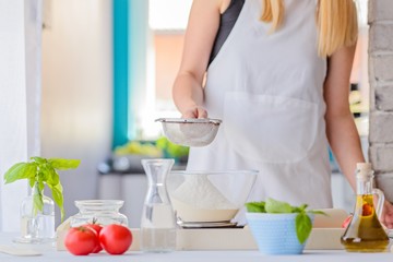 Woman sifting flour through sieve.