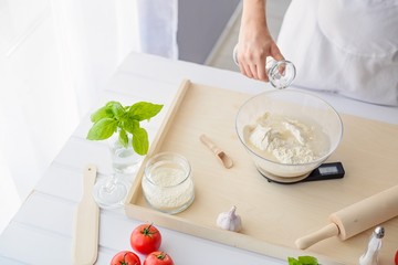 Woman adding water to flour in a bowl.