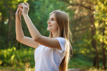 Pretty girl taking pictures in the forest. The girl with the cam