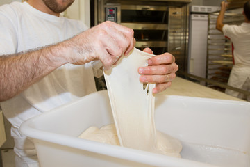 Making dough by man hands in bakery laboratory