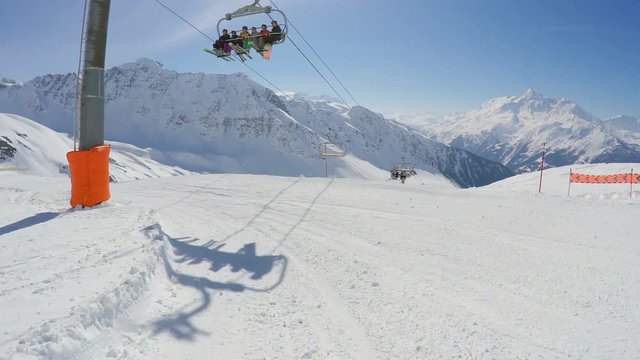 Skiing or snowboarding down a snowcross ski slope under a chairlift, beautiful weather French Alps in the background
