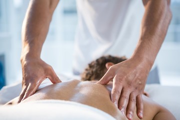 Woman receiving back massage from physiotherapist - obrazy, fototapety, plakaty
