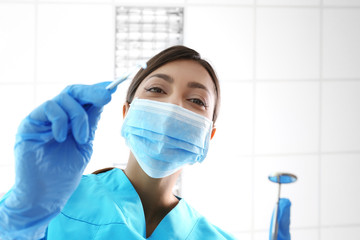 Portrait of young female dentist wearing surgical mask and holding checkup tools - Powered by Adobe