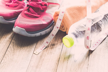 Sneakers, towel, water and tape measure on wooden floor