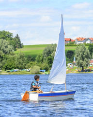 Obraz premium kleiner Junge beim Segeln mit seiner Jolle