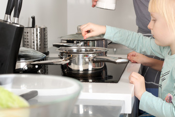 Small girl salting food with her father in the kitchen