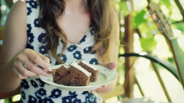 Girl sitting in the arbor and eating slice of cake
