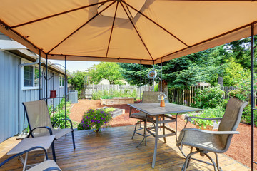 Backyard patio area with table set and opened orange umbrella