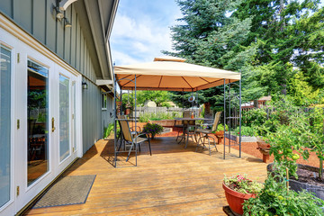 Backyard patio area with table set and opened orange umbrella