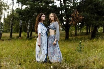 Fototapeta premium Young girls in ethnic clothes walking in fields. Fashion photo, folklore style