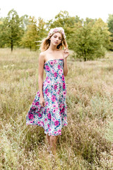 Fototapeta na wymiar Young girl in flower wreath walking in meadow