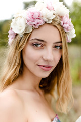 Naklejka premium Young girl in flower wreath walking in meadow