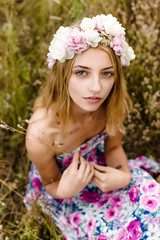 Fototapeta premium Young girl in flower wreath walking in meadow