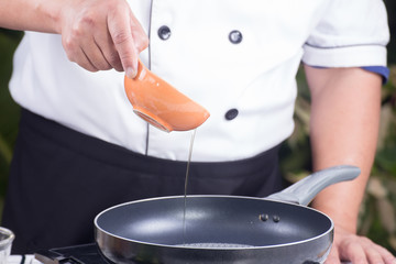 Chef pouring vegetable oil to the pan