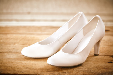 Pair of White Bridal Shoes on Rustic Wood Floor