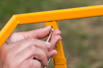 A caucasian woman is assembling furniture outdoors.