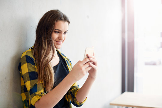 Young female student reading smartphone text at higher education college