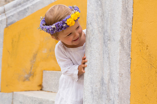 Female toddler wearing floral headdress peering from stairway, Beja, Portugal