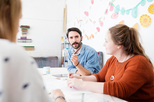 Female and male designer having brainstorm meeting in printing press studio