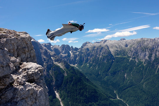Base jumper in wingsuit flying over mountains 