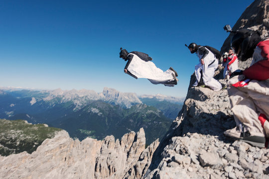 Wingsuit BASE jumping team jumping from cliff, Italian Alps, Alleghe, Belluno, Italy