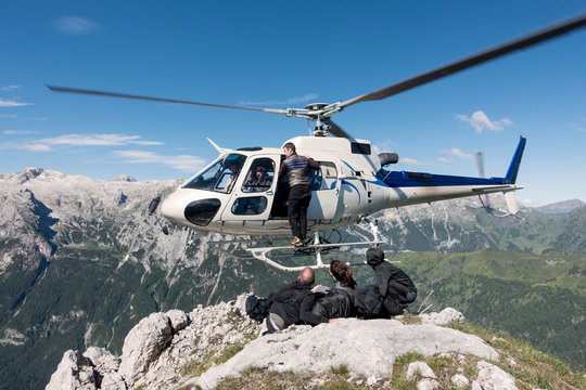 Male and female BASE jumping team exiting helicopter on top of mountain at Col di Pra, Italian Alps, Alleghe, Belluno, Italy