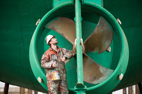 Worker standing in front of ship turbine in shipyard