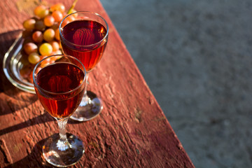 Two glasses of homemade rose wine and grapes on table at garden