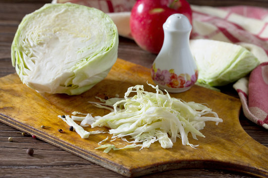 Sliced ​​cabbage and apple on old wooden table. In order to
