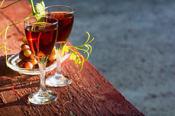Two glasses of homemade rose wine and grapes on table at garden